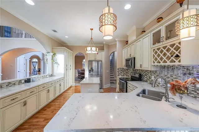 a large kitchen with stainless steel appliances a stove a sink dishwasher a dining table and chair with wooden floor