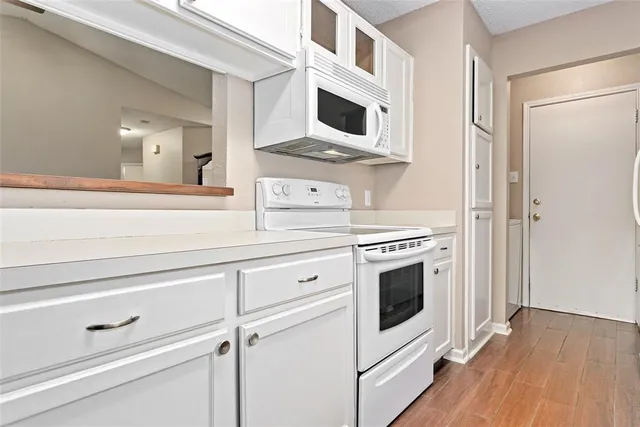 a kitchen with stainless steel appliances white cabinets and wooden floors