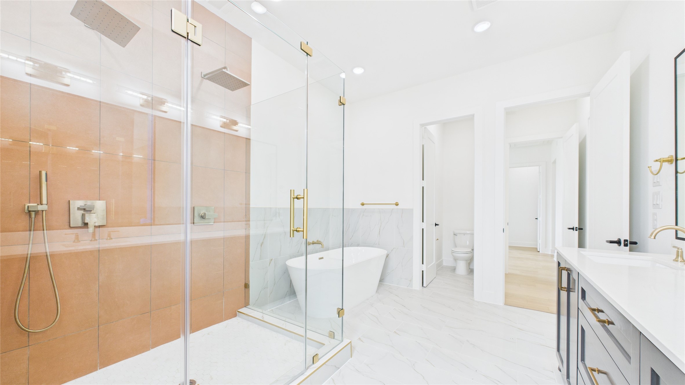 602 Jewett Street, Unit A Houston, TX 77009 - Photo 28 of 46 The spacious glass-enclosed shower offers dual rain showerheads, a sleek extra long freestanding bathtub, and elegant fixtures. The room is bright with a clean, minimalist design, offering ample space and a luxurious feel.