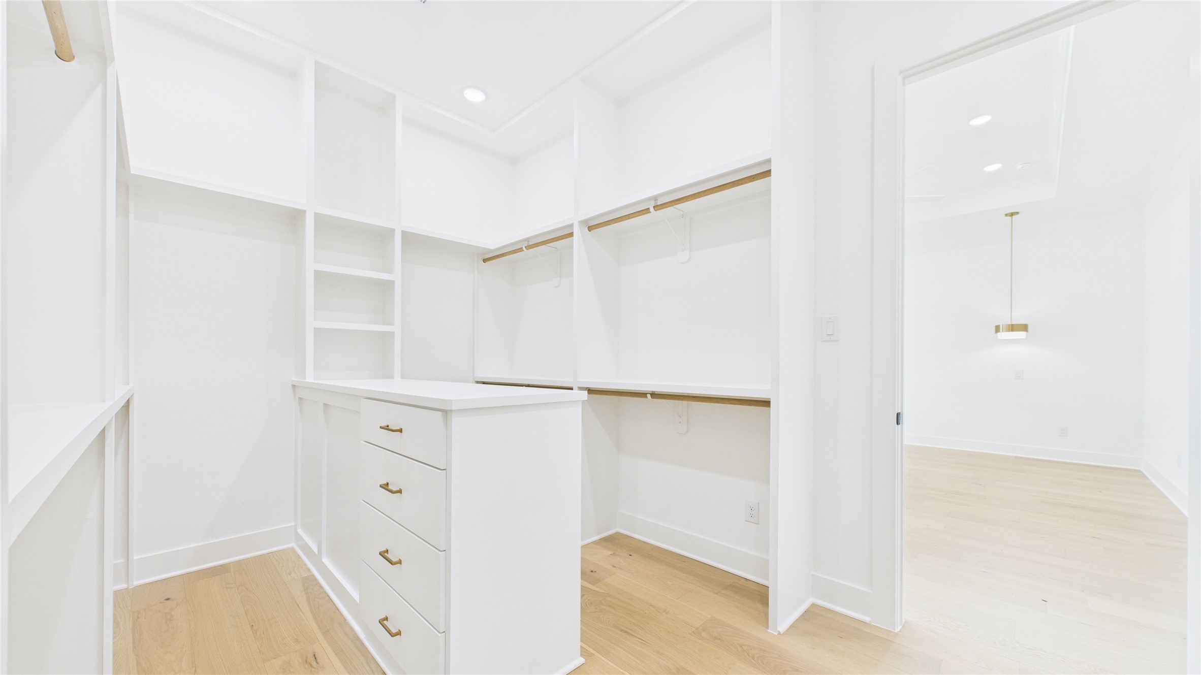 602 Jewett Street, Unit A Houston, TX 77009 - Photo 37 of 46 Spacious walk-in closet with ample shelving and hanging space, featuring a central drawer unit. Bright, white finish and recessed lighting create a clean, modern look.
