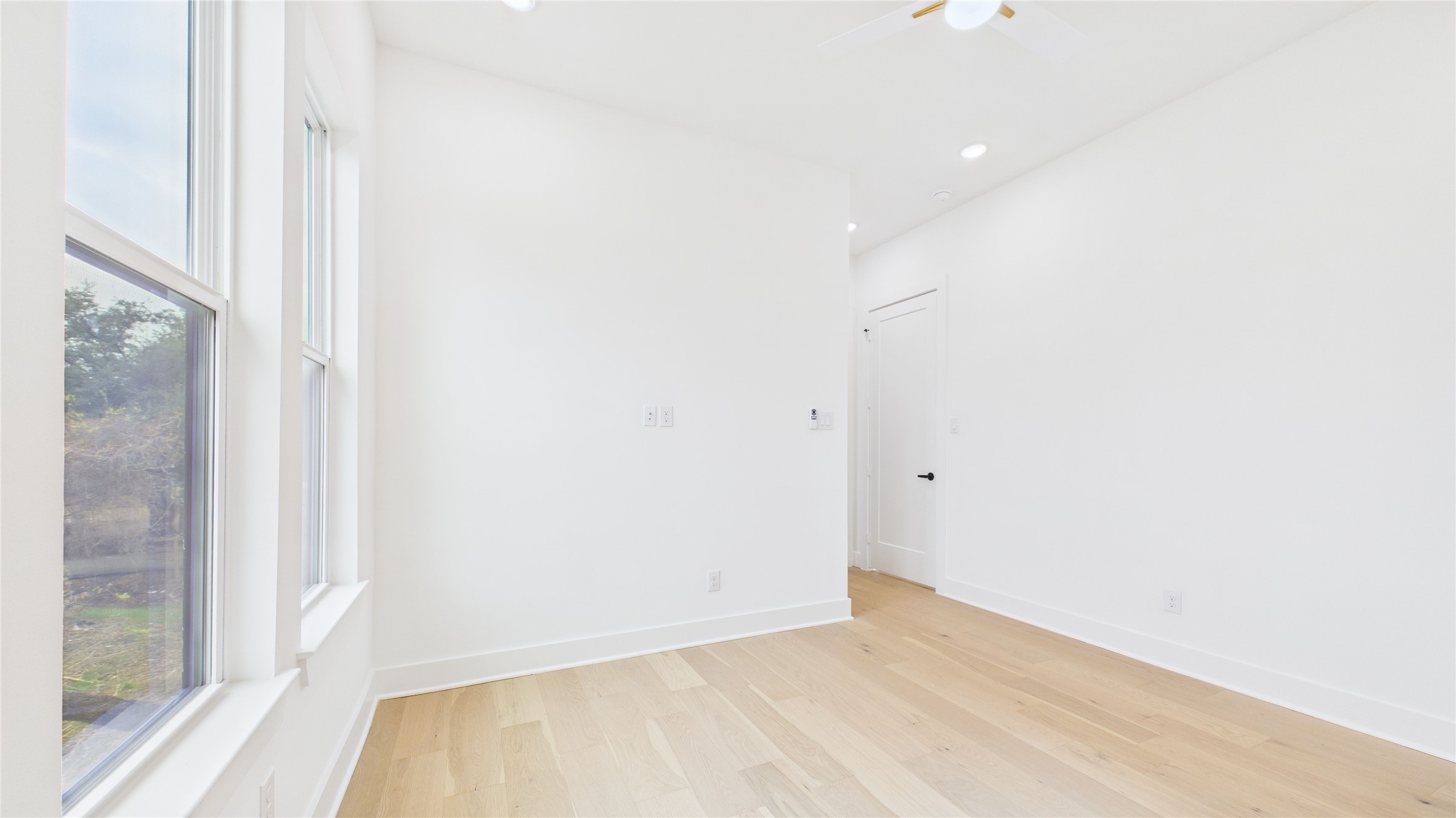 602 Jewett Street, Unit A Houston, TX 77009 - Photo 39 of 46 This room is bright and airy with large windows letting in natural light. It features light wood flooring and white walls, creating a clean, modern look. A ceiling fan is present, and there’s a door leading to another area.