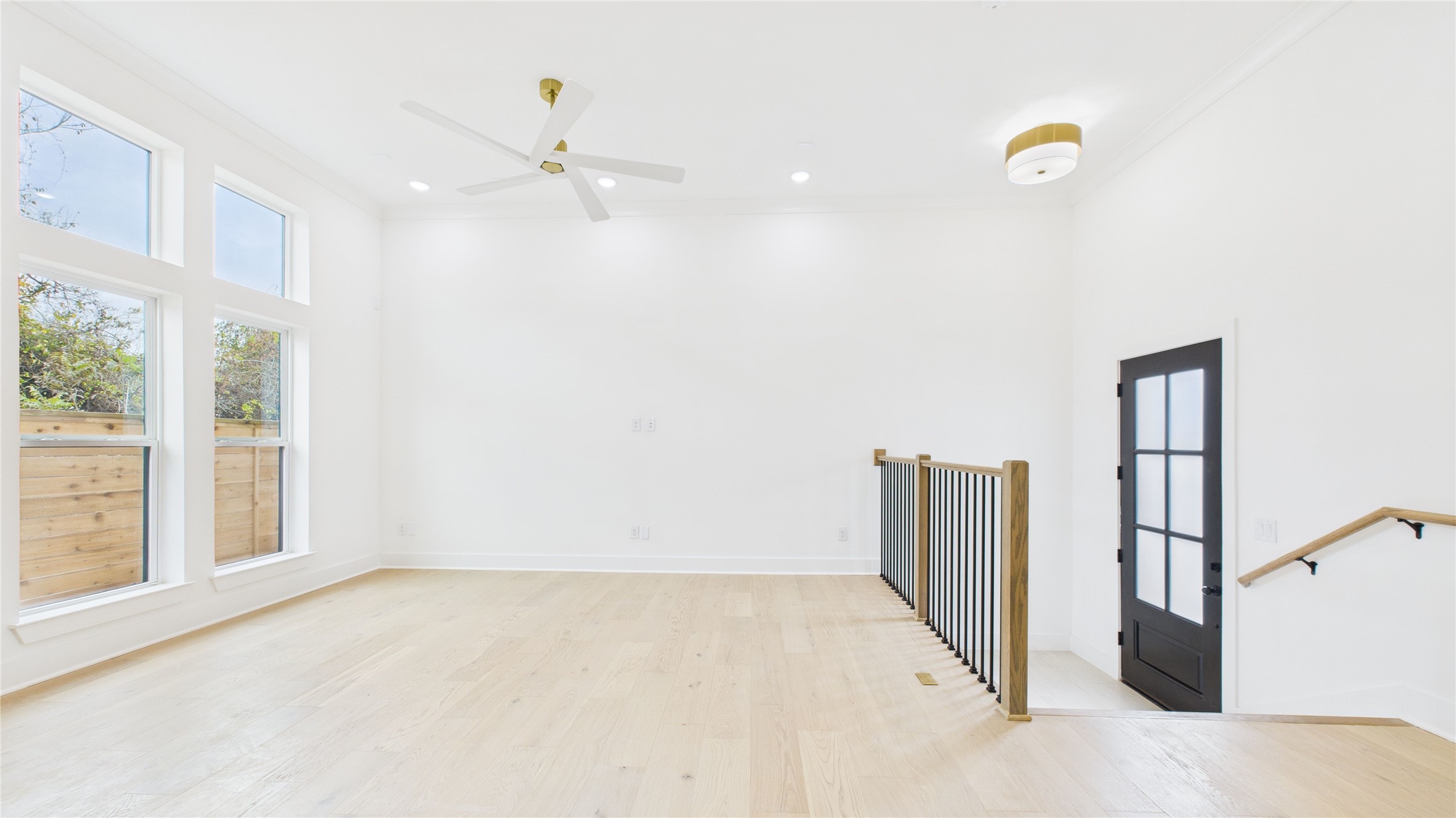 602 Jewett Street, Unit A Houston, TX 77009 - Photo 4 of 44 Bright, airy and open living space with high ceilings, large windows, and light wood floors. Features include a modern ceiling fan and a stylish black and opaque glass paneled door. Perfect for a contemporary home aesthetic.