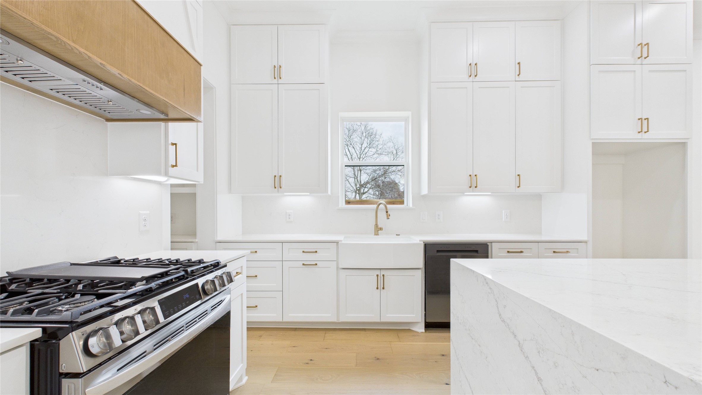 602 Jewett Street, Unit A Houston, TX 77009 - Photo 6 of 44 This kitchen features a premium LG stove with air fryer and convection, and a farmhouse sink. It includes a sleek quartz countertop and ample storage, gold fixtures and is illuminated by natural light from a central window.