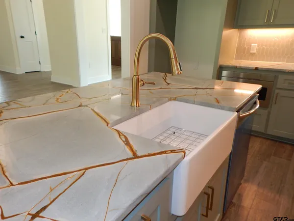 a kitchen with a sink and a stove with wooden floor