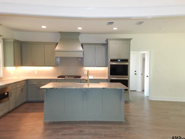 a kitchen with stainless steel appliances kitchen island granite countertop a stove and a sink