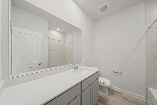 a bathroom with a granite countertop sink a toilet and a mirror
