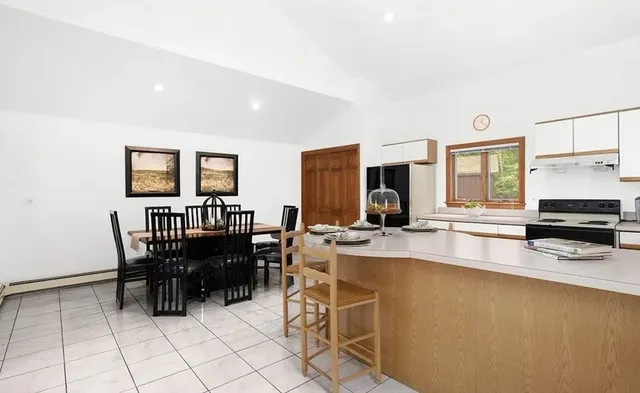 a kitchen with stainless steel appliances a dining table chairs and a refrigerator