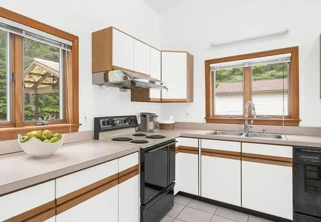 a kitchen with a sink a stove cabinets and a window