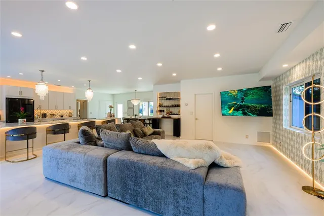 a living room with furniture a flat screen tv and kitchen view