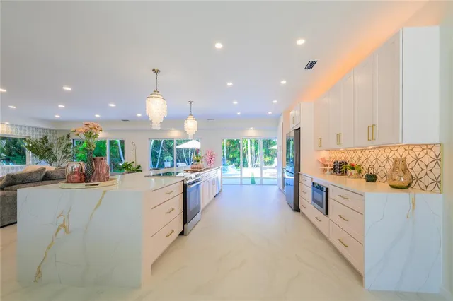 a large kitchen with stainless steel appliances a large counter top a stove and a sink