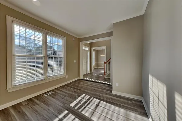 a view of an empty room with wooden floor and a window