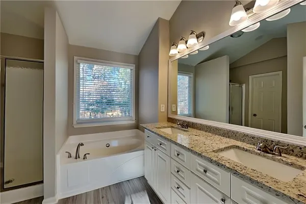 a bathroom with a granite countertop tub a double vanity sink and a large mirror