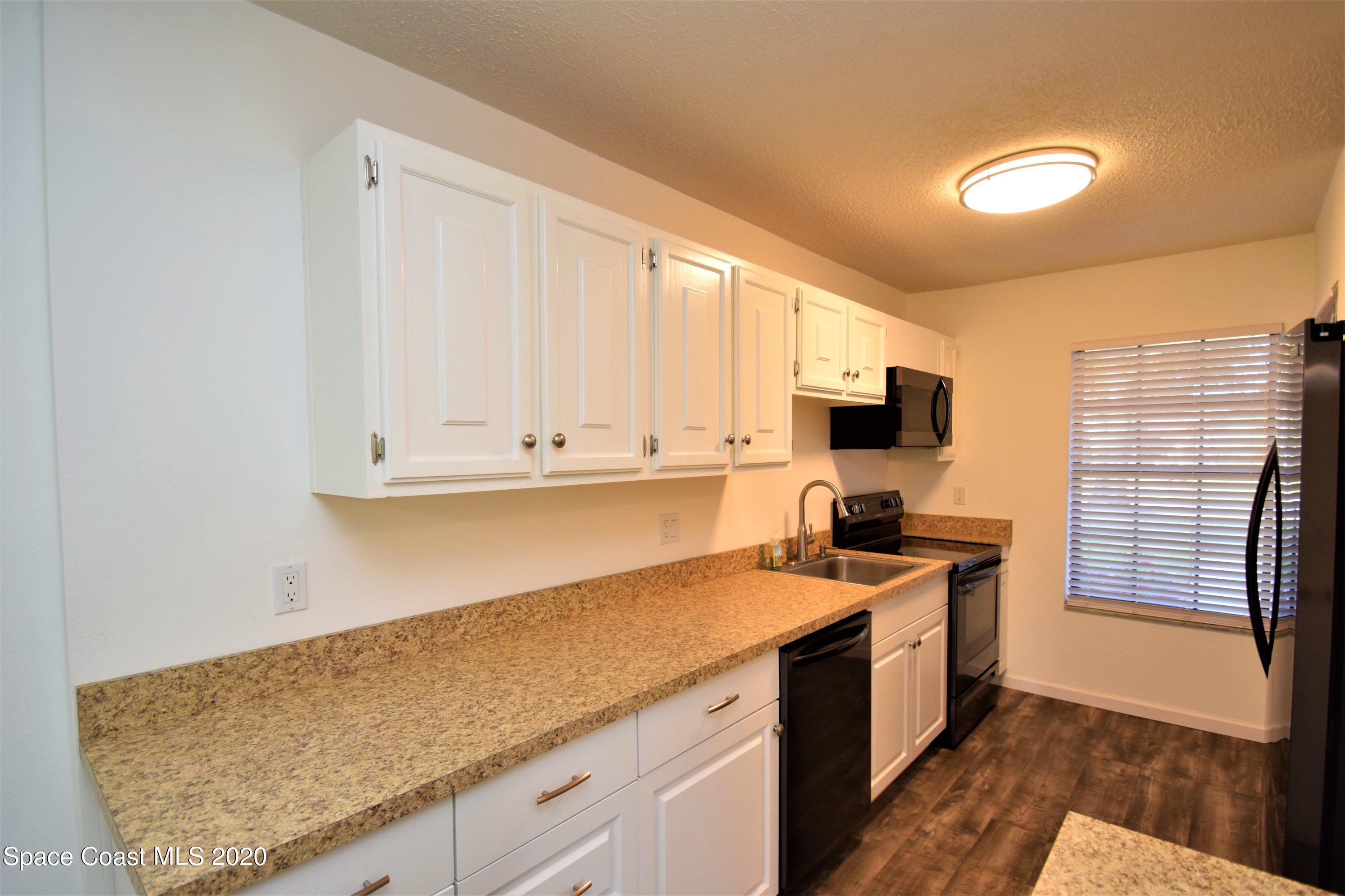 1654 Dawes Road Northeast Palm Bay, FL 32905 - Photo 12 of 47 a kitchen with granite countertop a sink stainless steel appliances and white cabinets
