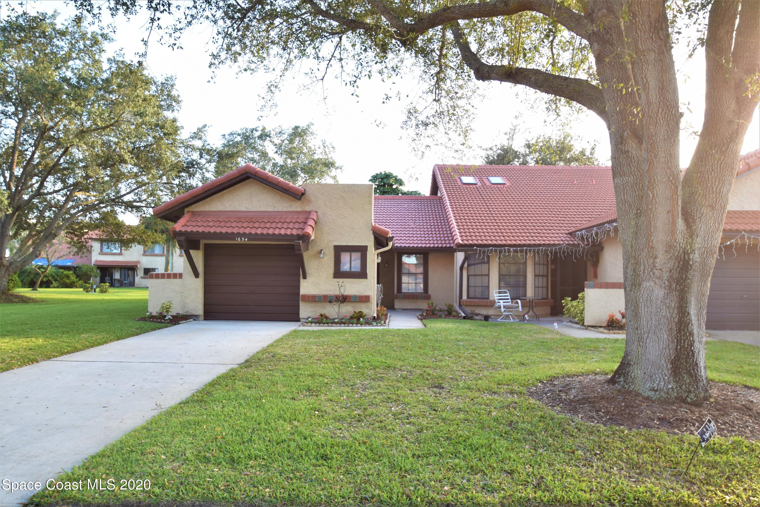 1654 Dawes Road Northeast Palm Bay, FL 32905 - Photo 3 of 47 a front view of a house with a garden and trees