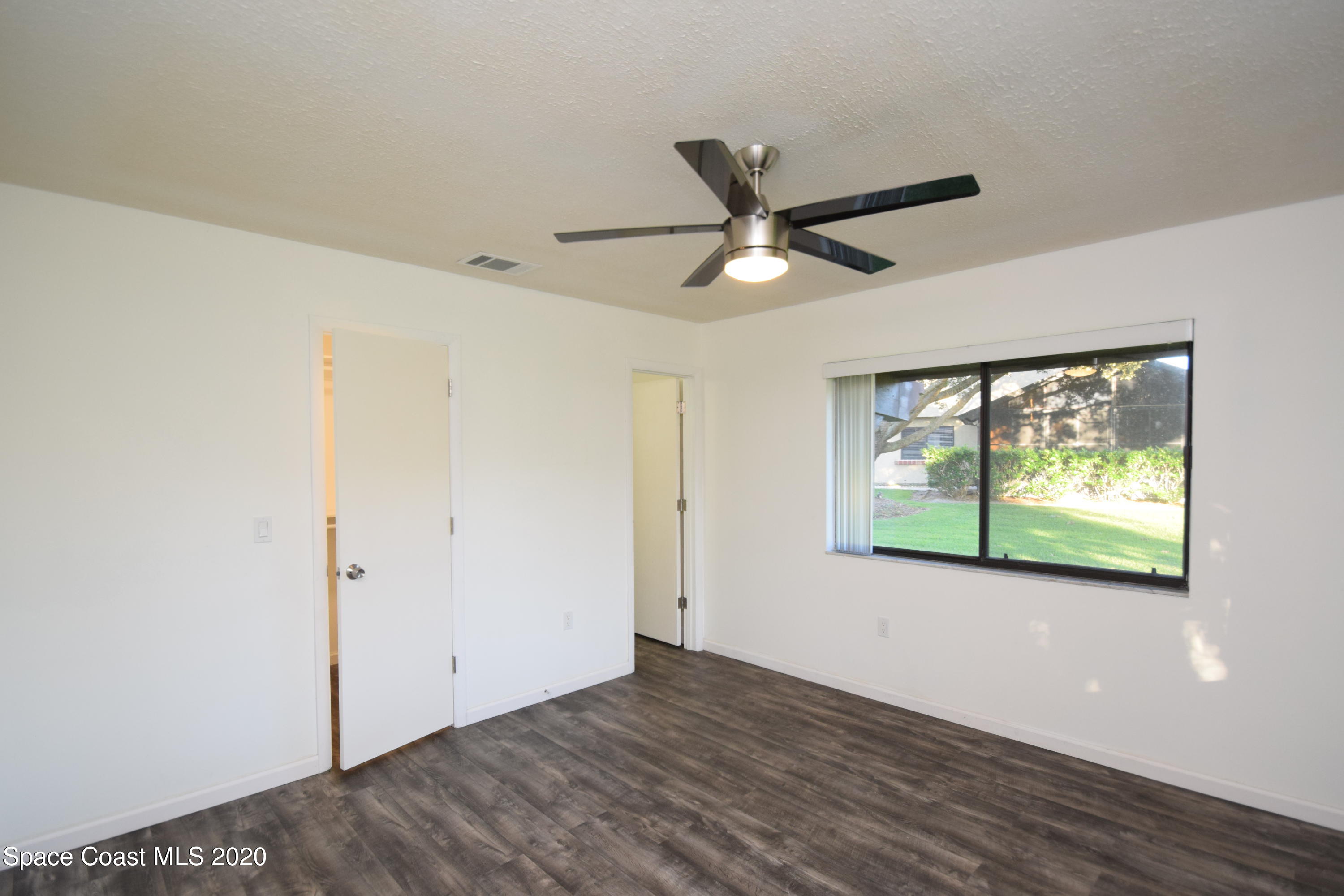 1654 Dawes Road Northeast Palm Bay, FL 32905 - Photo 25 of 47 an empty room with wooden floor fan and windows