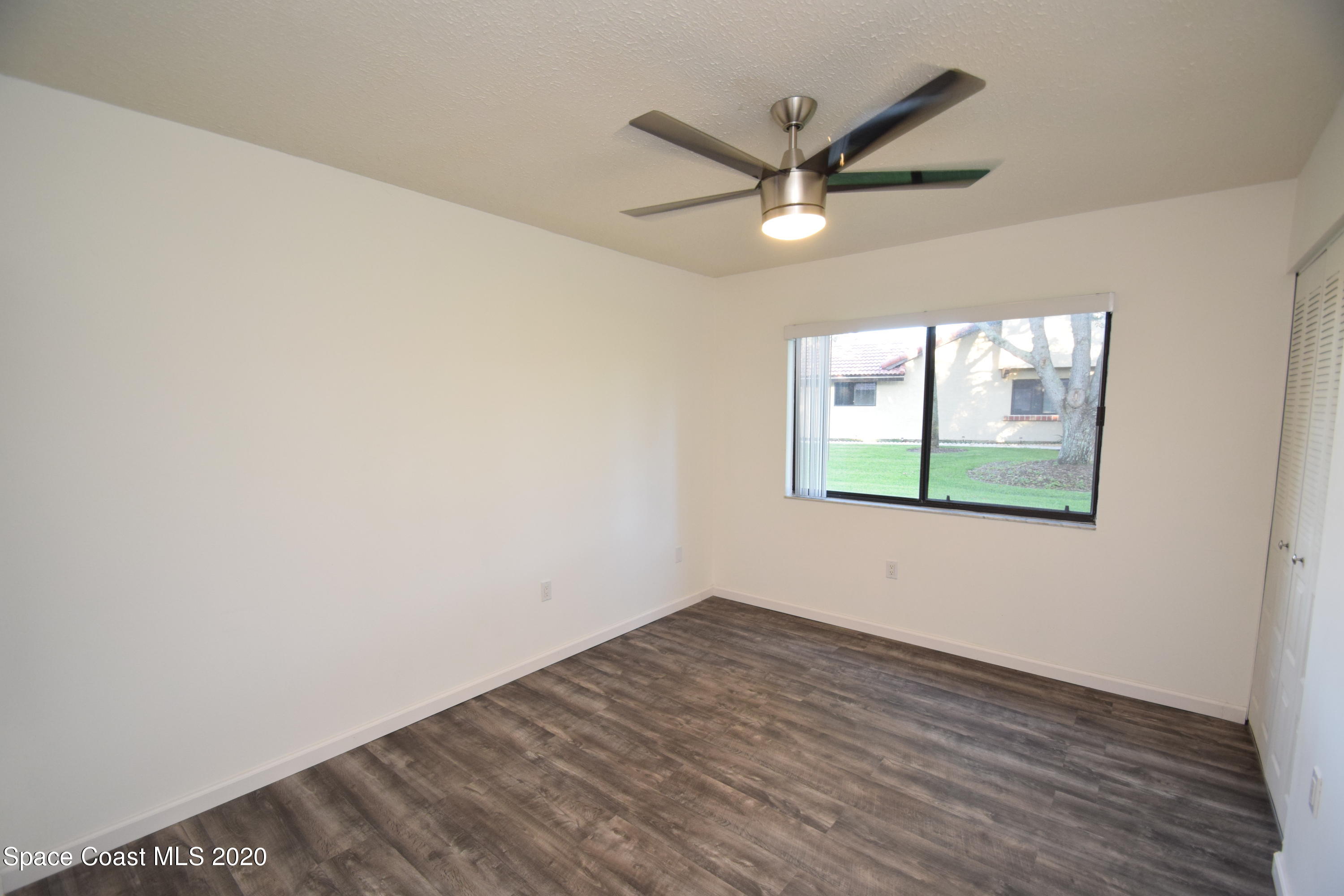 1654 Dawes Road Northeast Palm Bay, FL 32905 - Photo 31 of 47 an empty room with wooden floor fan and windows
