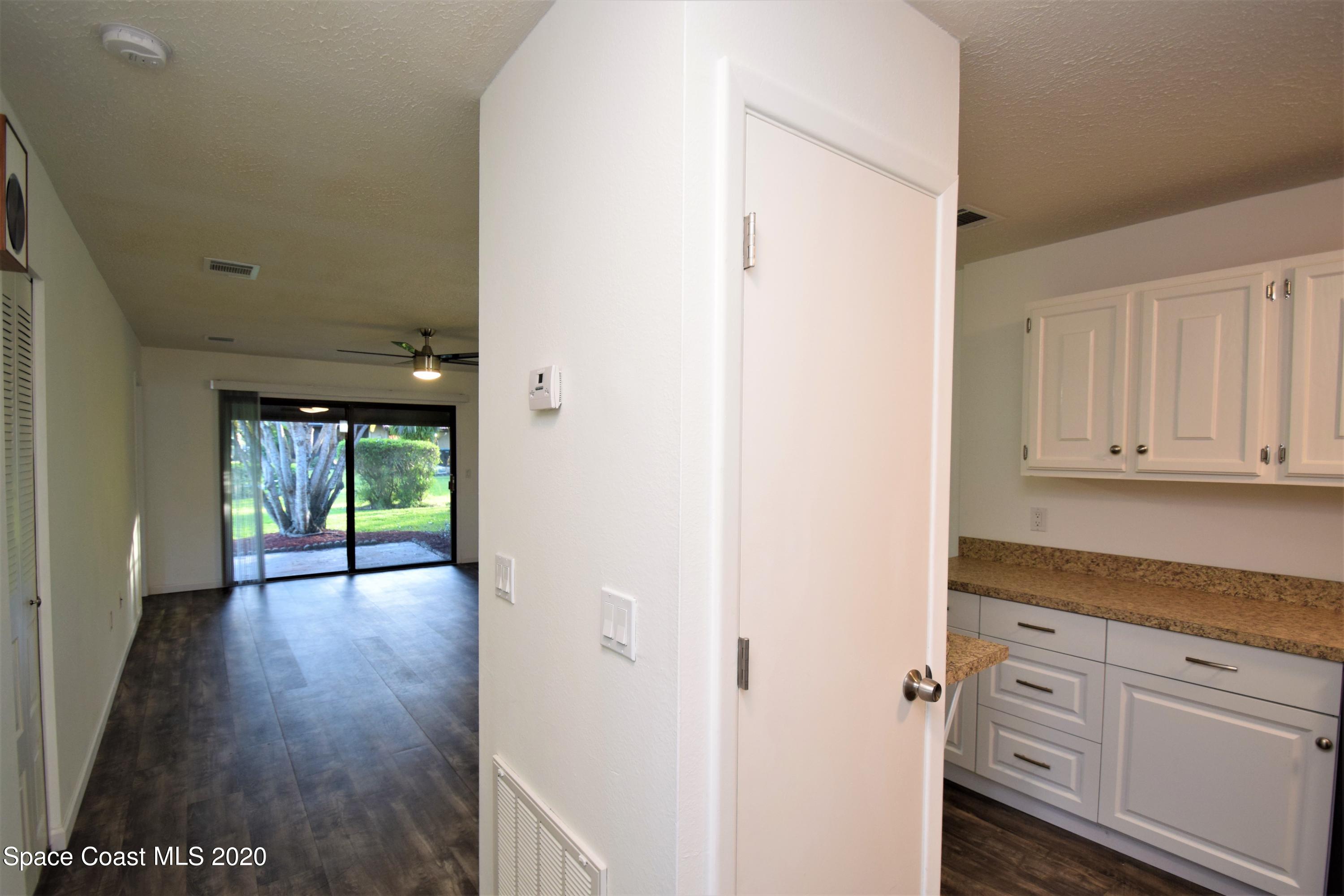 1654 Dawes Road Northeast Palm Bay, FL 32905 - Photo 8 of 47 a view of a hallway to an empty room with wooden floor and a cabinet