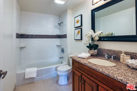 a bathroom with a granite countertop sink a toilet and bathtub