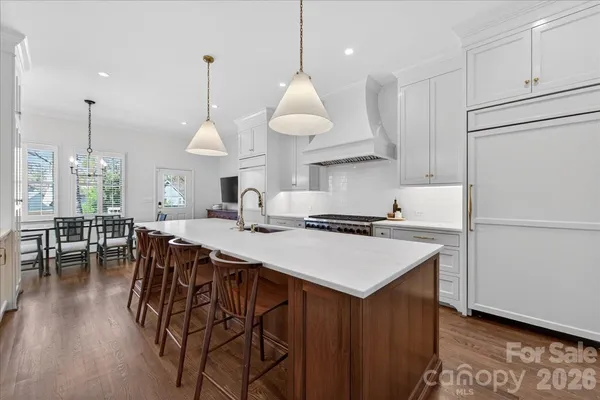 a kitchen with stainless steel appliances granite countertop a sink a stove a dining table and chairs