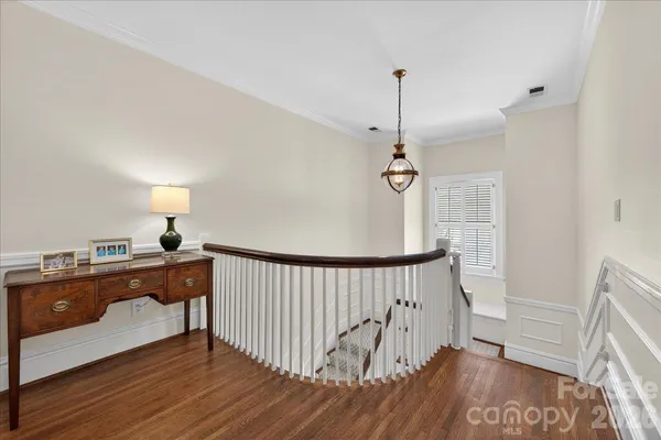 a view of hallway with wooden floor and a chandelier