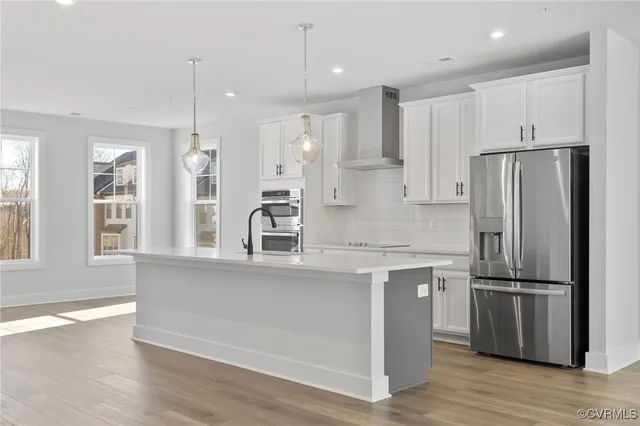 a kitchen with stainless steel appliances granite countertop a refrigerator a sink and white cabinets