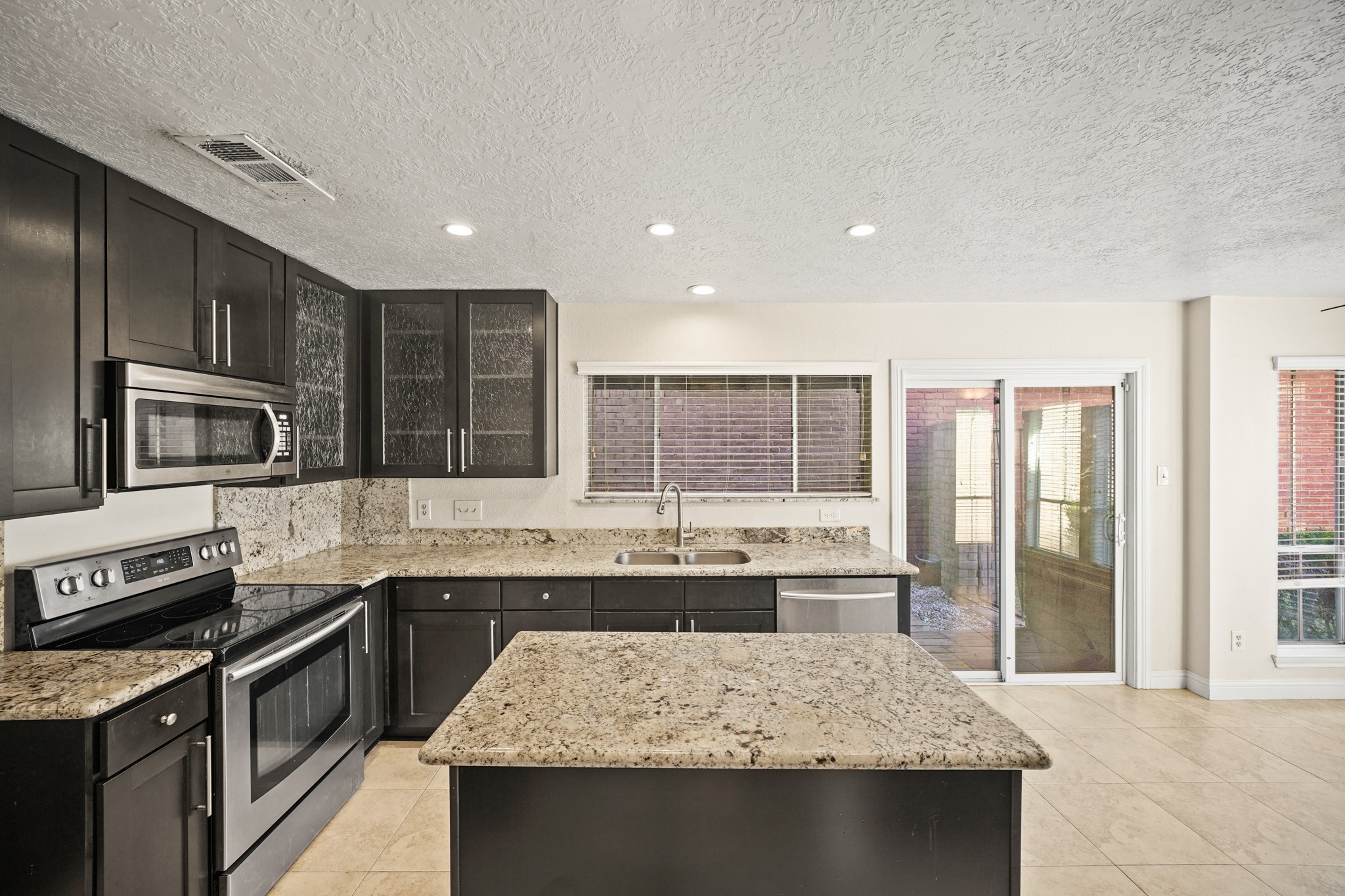 1641 Beaconshire Houston, TX 77077 - Photo 13 of 27 This bright and open kitchen flows seamlessly into the breakfast room, creating a functional and inviting space for everyday living. A spacious center island provides additional prep space and casual gathering room, while recessed lighting keeps the entire area well-lit.