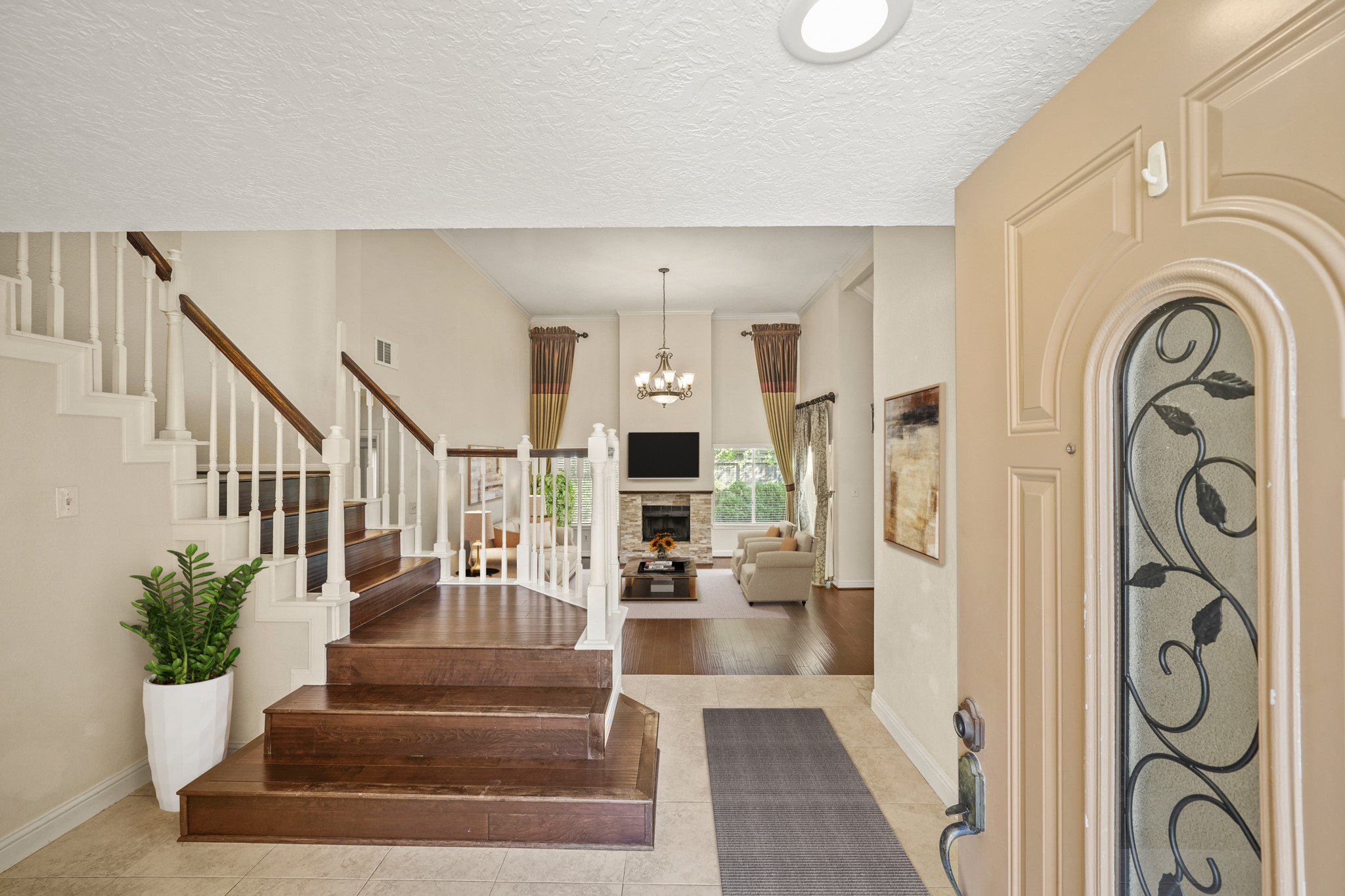 1641 Beaconshire Houston, TX 77077 - Photo 6 of 27 Virtually Staged: Step inside to a bright and welcoming foyer featuring elegant tile flooring, crisp white trim, and rich wood steps that lead into the main living area. The split-level design adds architectural interest, while the staircase with wood handrails and white spindles creates a timeless, classic look.