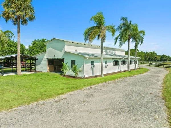 a view of a house with a yard and palm trees
