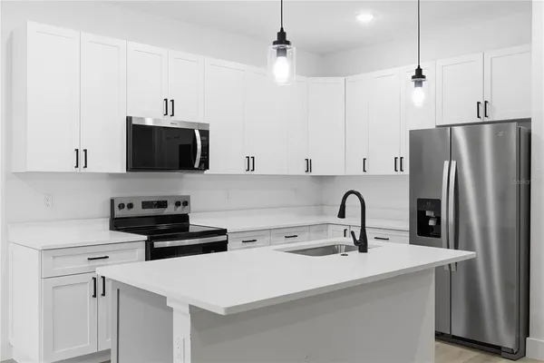 a kitchen with stainless steel appliances a sink a stove a refrigerator a center island with cabinets and wooden floor