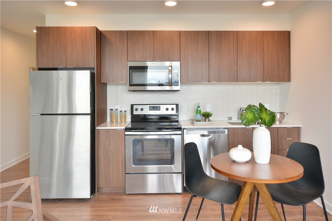 1601 North 45th Street, Unit 411 Seattle, WA 98103 - Photo 22 of 33 a kitchen with stainless steel appliances granite countertop a refrigerator a stove a microwave a sink and chairs