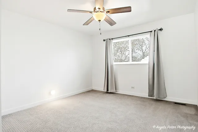 an empty room with a window and a fan
