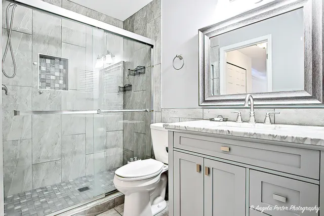 a bathroom with a granite countertop sink a toilet and shower