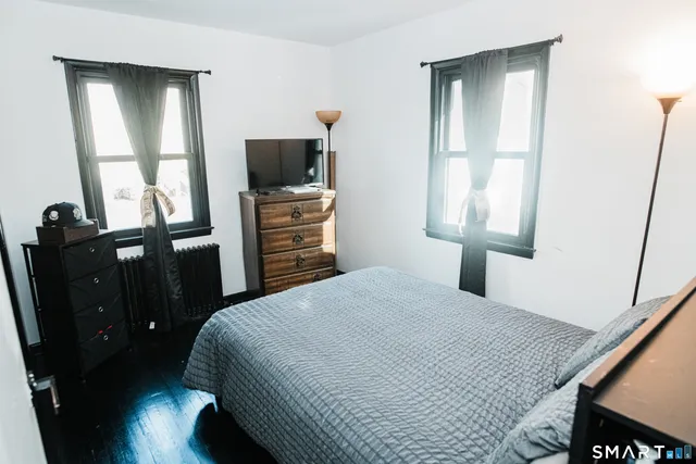 a bedroom with a bed and a flat tv screen on dresser