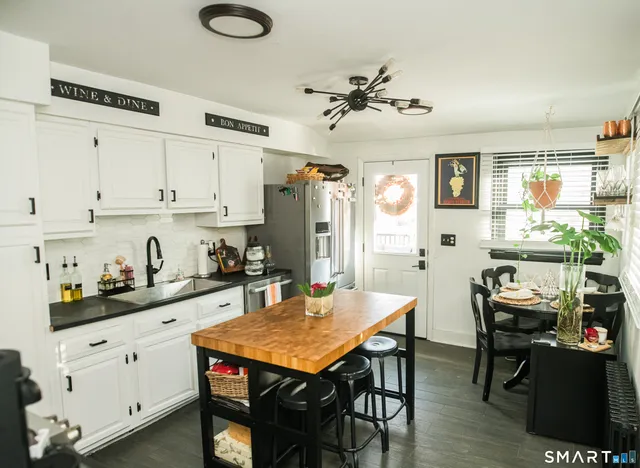 a kitchen with stainless steel appliances granite countertop a stove a sink dishwasher and white cabinets with wooden floor