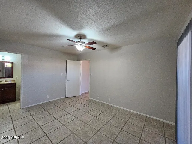 a view of an empty room and chandelier fan
