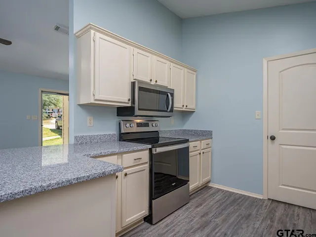 a kitchen with granite countertop a stove a sink and a microwave