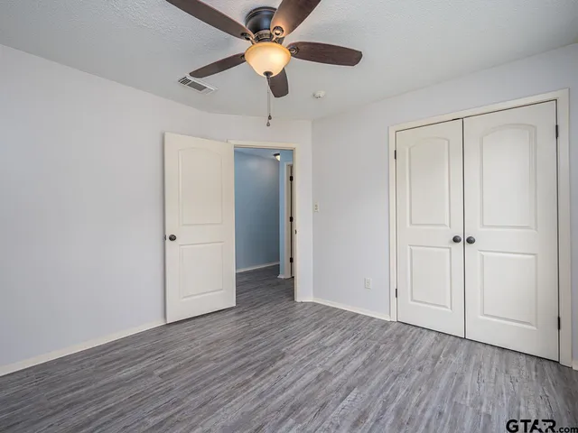 an empty room with wooden floor a ceiling fan and closet