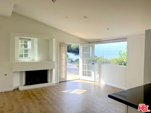 a view of empty room with wooden floor and fireplace