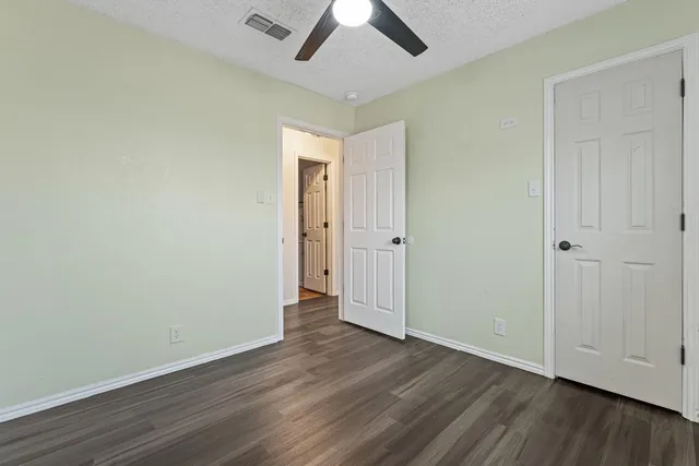 an empty room with wooden floor a ceiling fan and closet
