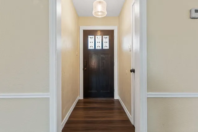 a view of a hallway with wooden floor and a front door