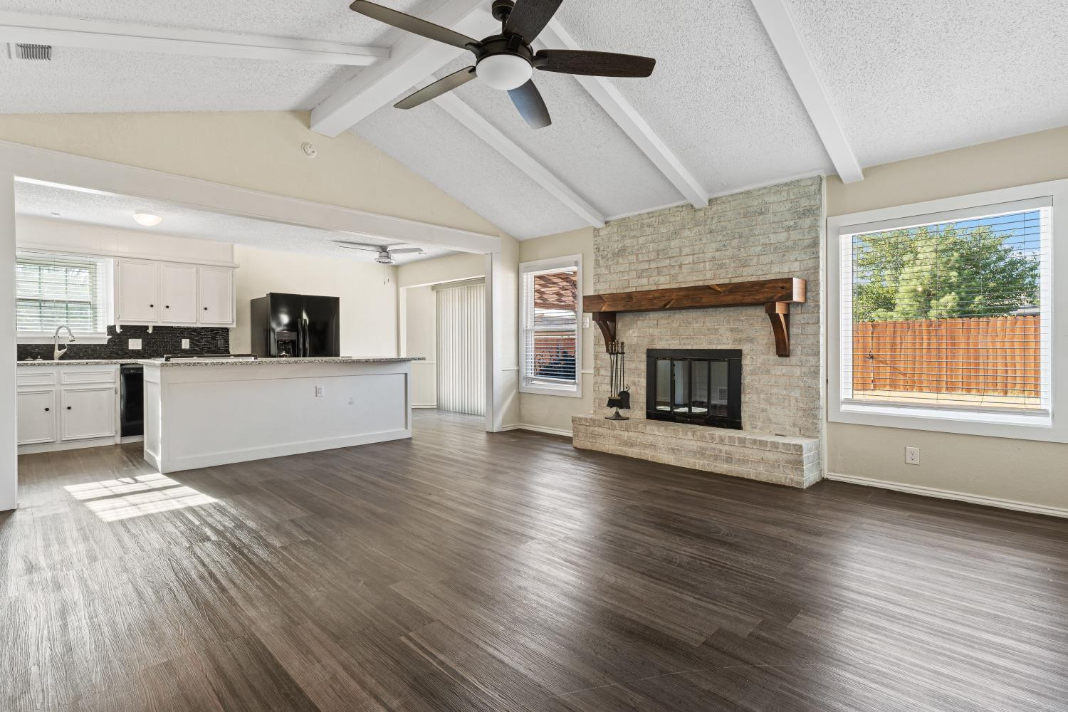 6154 38th Street Lubbock, TX 79407 - Photo 5 of 23 a view of a room with kitchen and fireplace wooden floor