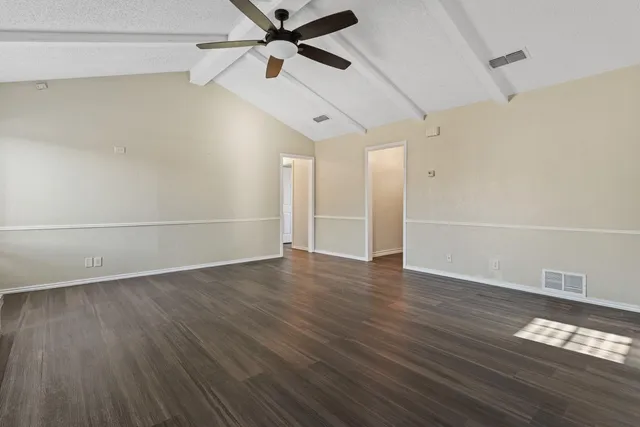 an empty room with wooden floor fan and windows