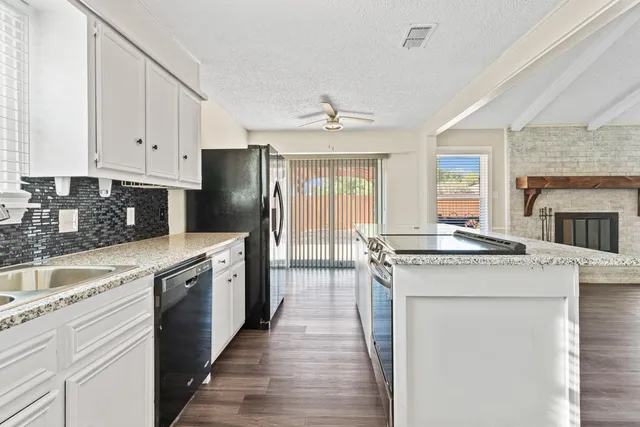a kitchen with granite countertop a sink stove and refrigerator