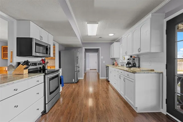 a kitchen with granite countertop a stove top oven a sink dishwasher and a refrigerator with wooden floor