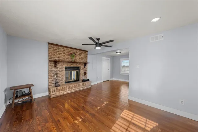 a view of an empty room with wooden floor and a fireplace