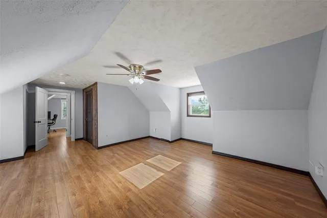 an empty room with wooden floor chandelier fan and windows