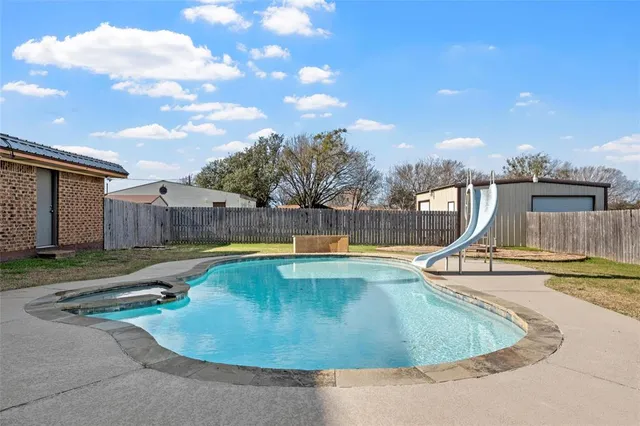 a view of a swimming pool with a yard and a wooden fence
