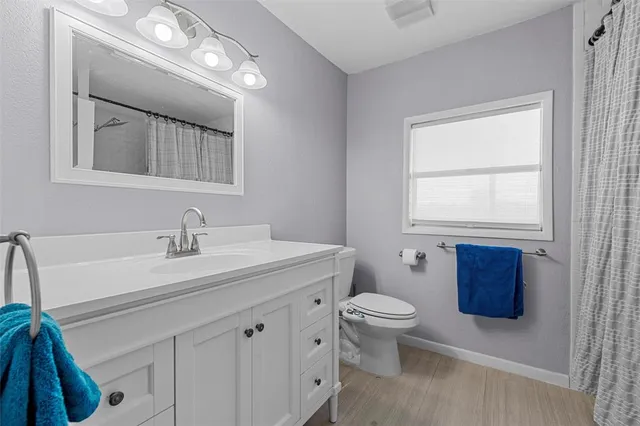 a bathroom with a toilet a sink a mirror a window and vanity