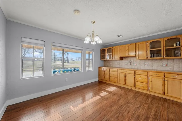 a spacious bathroom with stainless steel appliances granite countertop a sink dishwasher a stove and white cabinets with wooden floor