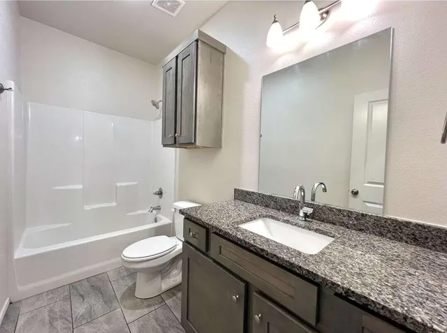 a bathroom with a granite countertop sink a toilet and shower